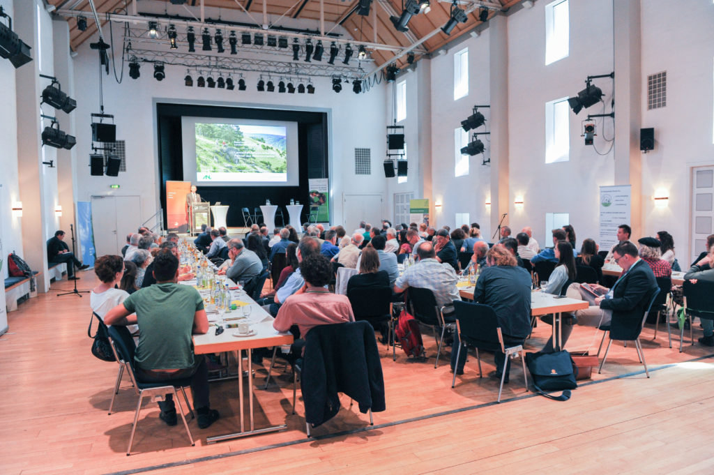 Blick auf die Bühne über den gefüllten Vortragssaal beim Bayerischen Landschaftspflegetag 2018 in Eichstätt.