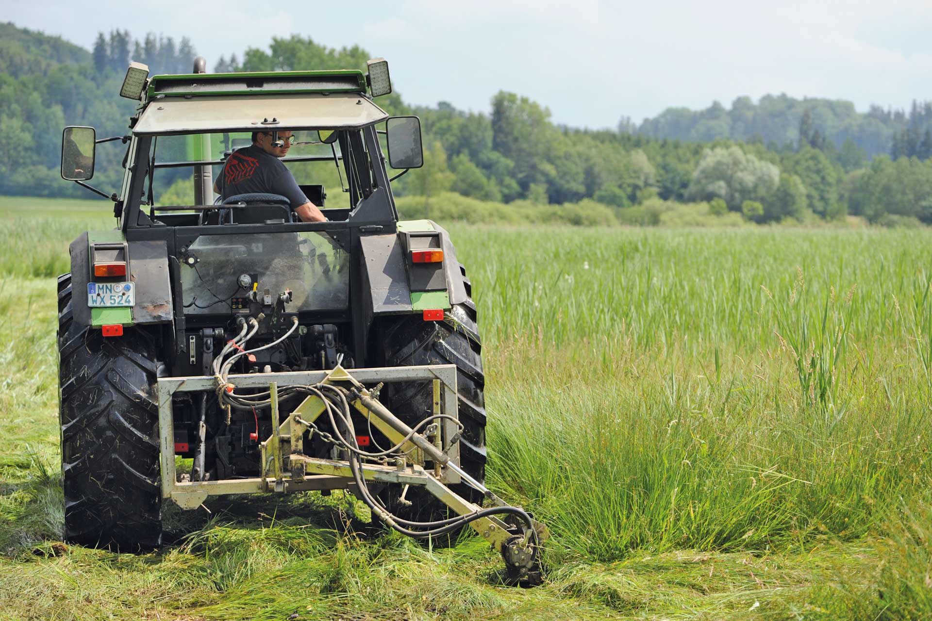 A tractor in a field. It's being mowed.