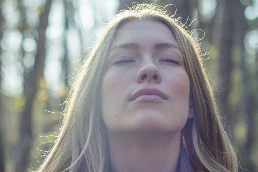 A woman is standing in a forest and inhales the fresh air.