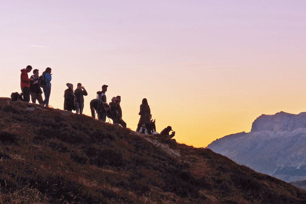 Young people on a hill. The sun is setting in the background.