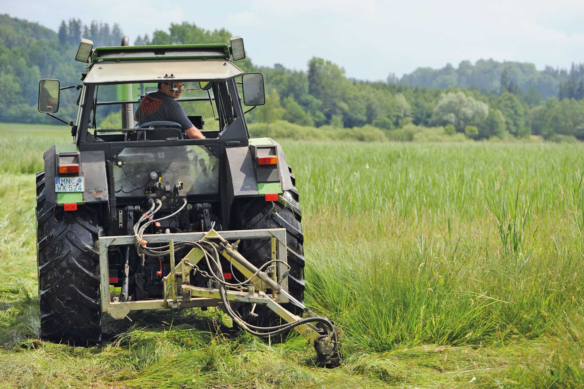 Ein Traktor auf einem Feld. Hier wird gemäht.