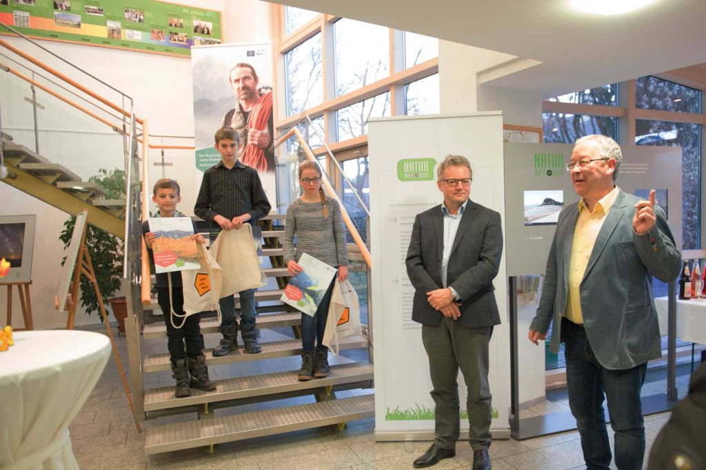 Zwei Buben uind ein Mädchen stehen auf einer Treppe im Foyer des ANL-Verwaltungsgebäudes und zeigen ihre Urkunden. Rechts vorne sthen Dr. Michael Apel und Dieter Pasch.