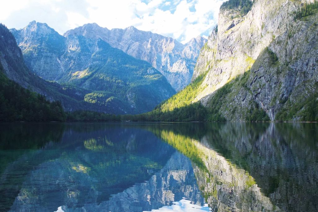 A lake in front of a mountain landscape. The mountains are reflected in the water.