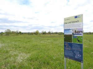 Auf dem Bild ist eine Natura 2000 Tafel zu sehen mit Informationen zum europäischen Naturerbe, die Tafel steh im Gebiet "Paar und Ecknach"