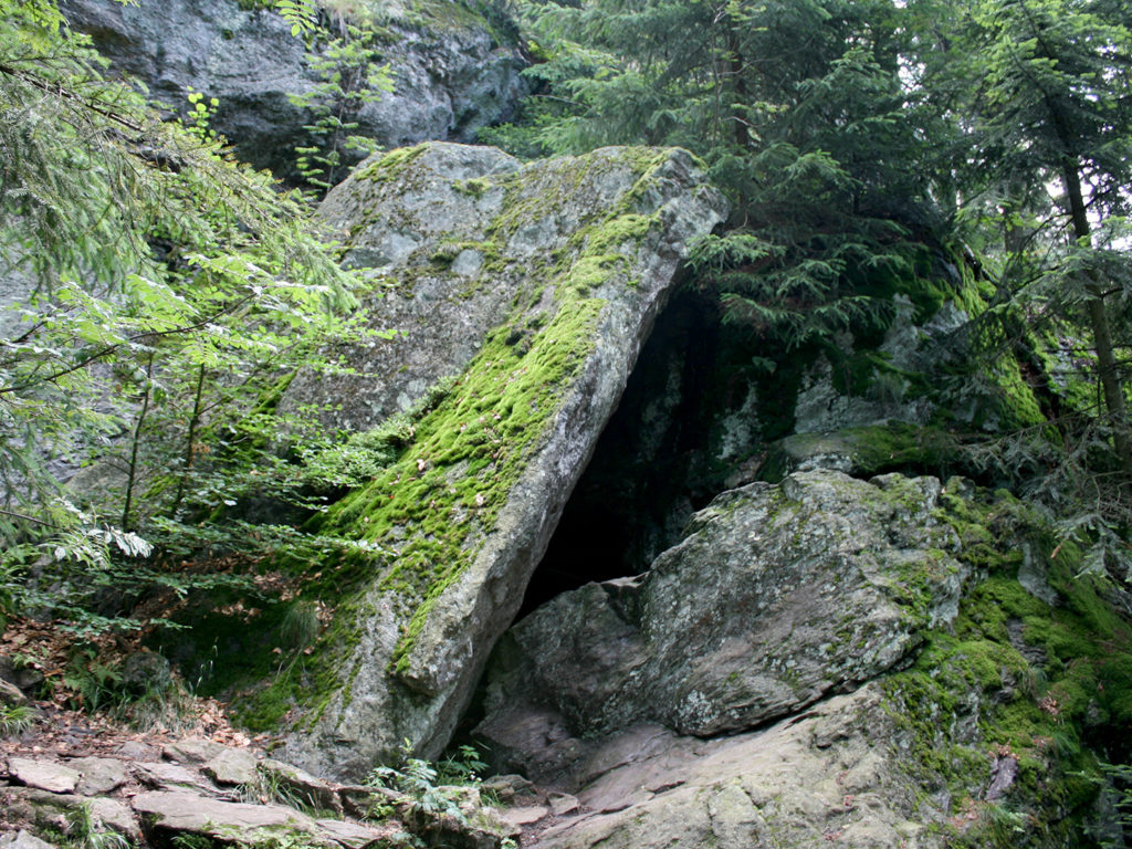 Auf dem Bild ist eine Felshöhle zu sehen, die durch Gesteinsplatten gebildet wird.