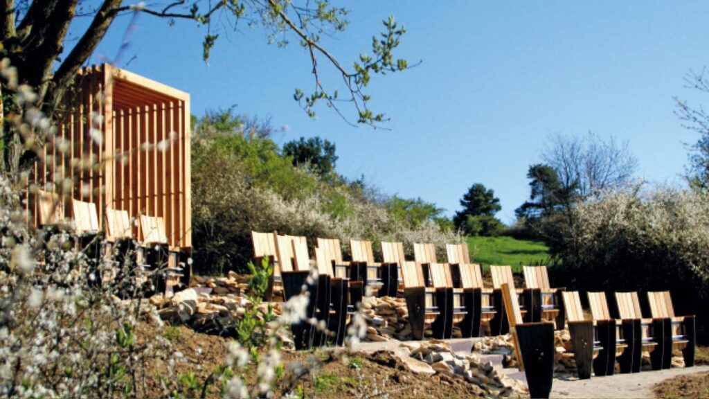 Vier Reihen Holzstühle sehen am Hang mit Aussicht auf das Tal.