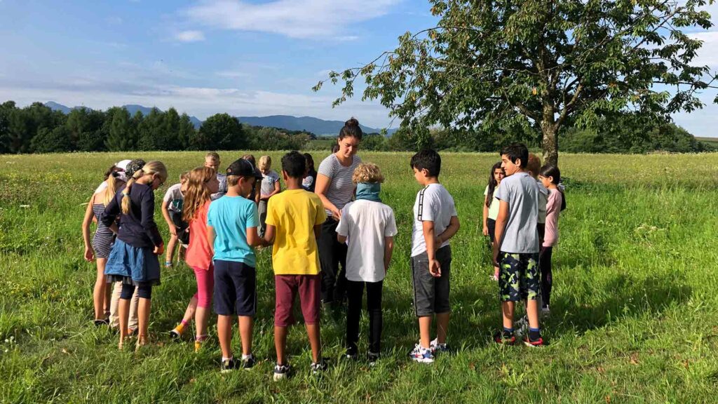 Eine Schulklasse steht auf einer Wiese