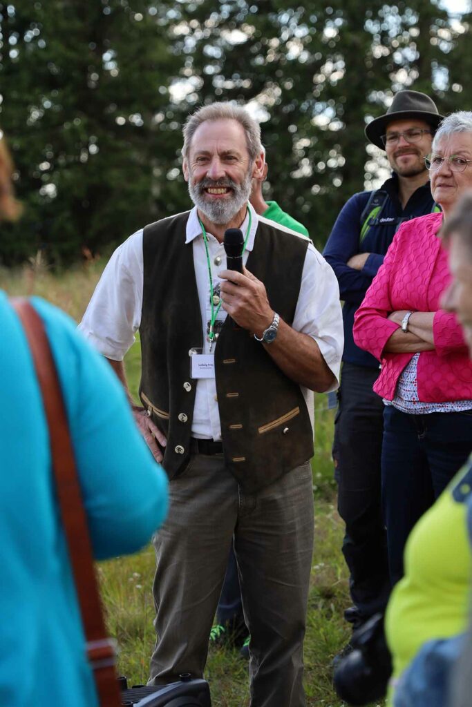 Weiderechtler und Landwirt Ludwig Fritz erklärt den Teilnehmerinnen und Teilnehmern der Veranstaltung die Vorteile und Anstrengungen für eine Beweidung einer Schachtenwiese.