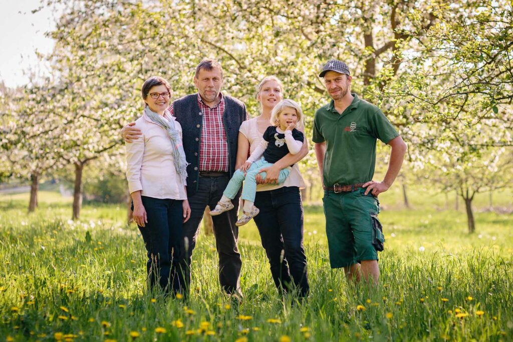 Familienportrait der Familie Stöckl - drei Generationen stehen auf einer blühenden Streuobstwiese.