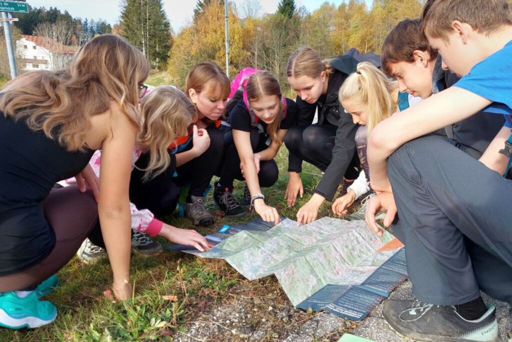 Eine Gruppe Jugendliche kniet rund um eine Landkarte am Boden.