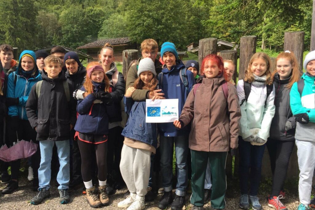 Schülerinnen und Schüler stehen und halten einen Zettel mit den Logos von LIFE und Natura 2000.