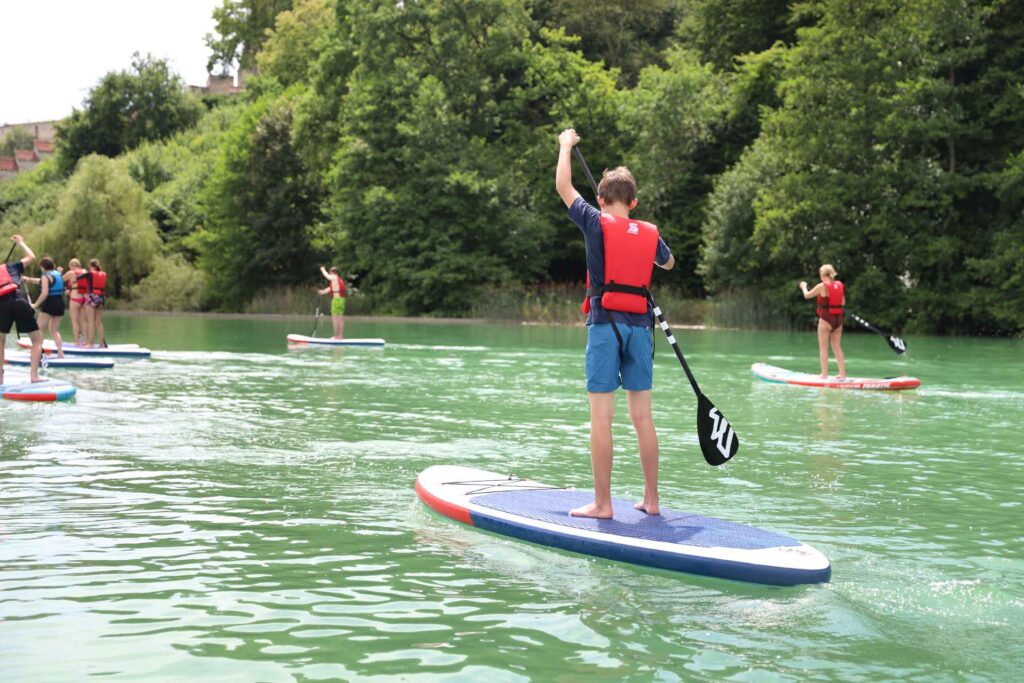 Schülerinnen und Schüler paddeln mit Stand-up-Boards über den Wöhrsee.