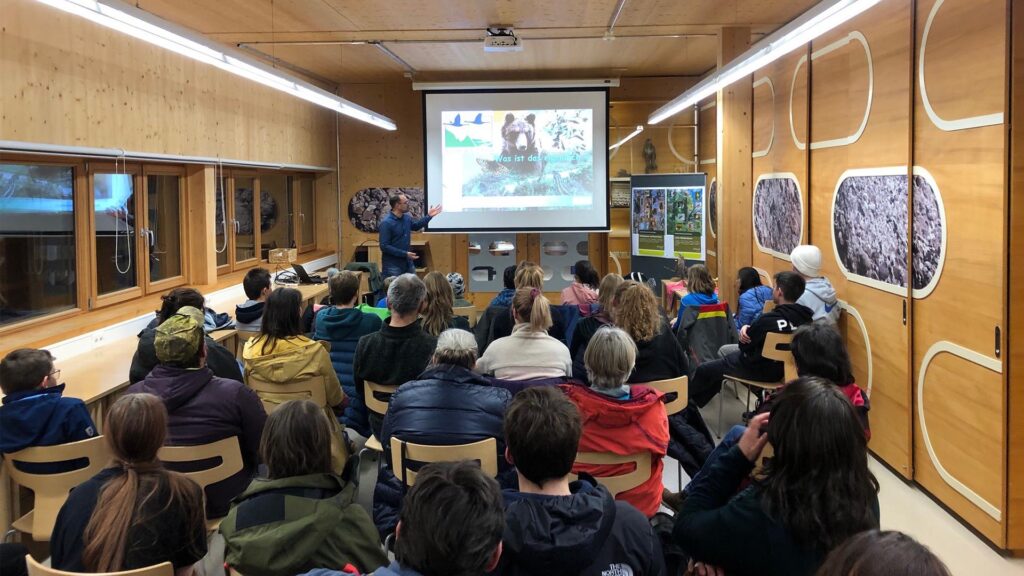 Teilnehmerinnen und Teilnehmer sitzen in einem Saal vor einer Leinwand mit dem Titel: Was ist Natura 2000?